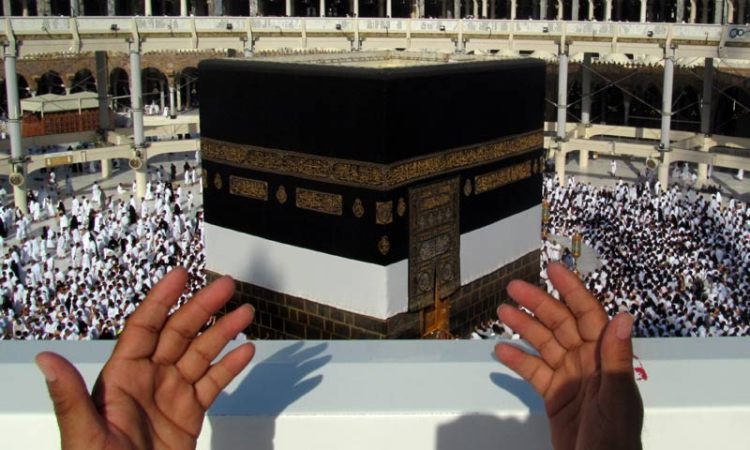 A Hajj pilgrim praying and supplicating towards the Ka'bah.